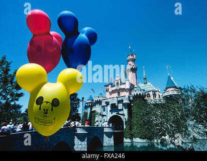 Ballons colorés avec le visage de Mickey Mouse flotter en face de Château de La Belle au bois dormant, une imposante structure de conte de fées qui est l'élément central de l'économie la plus célèbre parc à thème, Disneyland, qui a ouvert ses portes en 1955 à Anaheim, Californie, USA. Le bâtiment a été conçu d'après un vrai château de Neuschwanstein, en Allemagne, construit à la fin des années 1800 comme un palais pour le roi Louis II de Bavière. Disneyland a été la création de Walt Disney, un entrepreneur américain bien connu et cinéaste qui a créé Mickey Mouse et autres personnages emblématiques. Banque D'Images