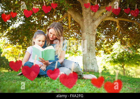 Image composite de mère et fille lire un livre du park Banque D'Images