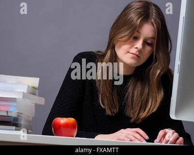 Belle jeune femme dans un bureau à travailler sur un ordinateur Banque D'Images