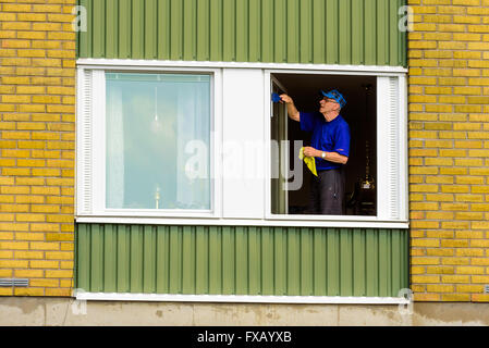 Kivik, Suède - 7 Avril, 2016 : nettoyage des fenêtres dans un appartement. Fenêtre est ouverte et l'homme engrange de l'eau fro Banque D'Images