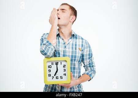 Homme fatigué endormi les bâillements et holding réveil sur fond blanc Banque D'Images