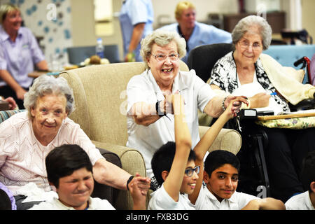 Les enfants de l'école visite d'une maison de soins de personnes âgées pour développer les relations intergénérationnelles. Banque D'Images