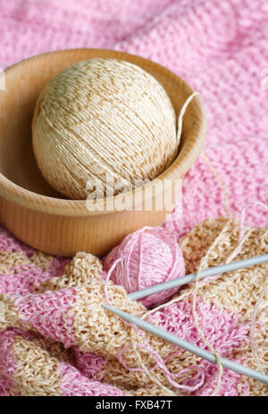 Belle écharpe en tricot à rayures, des aiguilles à tricoter et les deux billes de la laine sur un tableau blanc. Boules de laine couché dans un bol en bois. Yar Banque D'Images