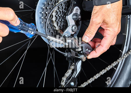 Man adjusting bicycle gear dérailleur avec des outils libre Banque D'Images