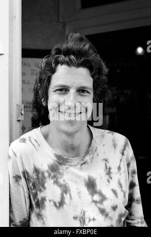 Homme aux cheveux longs souriante portant un t-shirt tie dye en angleterre Banque D'Images