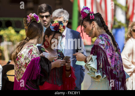 Séville, Espagne. 14 avr, 2016. Trois femmes habillées avec robe flamenco typique d'utiliser leurs téléphones mobiles à la ''Feria de Abril'' (avril 2016) du salon © Daniel Gonzalez Acuna/ZUMA/Alamy Fil Live News Banque D'Images