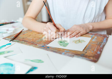 Libre de mains de femme artiste peinture avec pinceau et aquarelle peint sur la table Banque D'Images