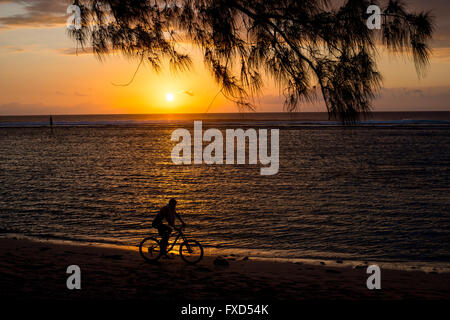 Une des promenades en vélo de montagne le long d'une plage sur l'île de la réunion dans l'Océan Indien au coucher du soleil. Banque D'Images