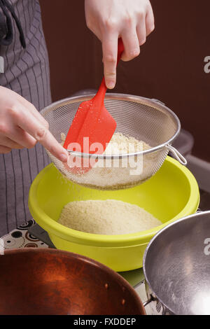 Mains tamise la farine dans le bol de cuisson gâteau pour Banque D'Images