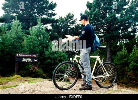 Adolescent en regardant une carte sur un sentier dans les Cairngorms, Aviemore, Ecosse, Royaume-Uni. Banque D'Images