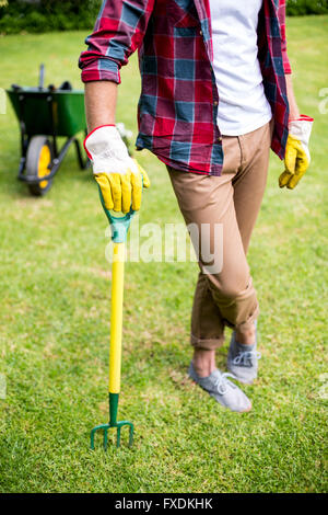 Homme debout avec rake in yard Banque D'Images