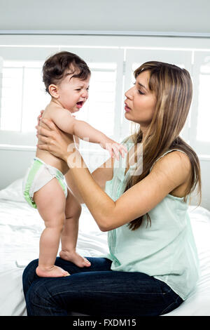 Mère avec fils pleurer sur le lit chez lui Banque D'Images