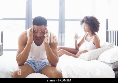 L'homme se crispa sitting on bed Banque D'Images