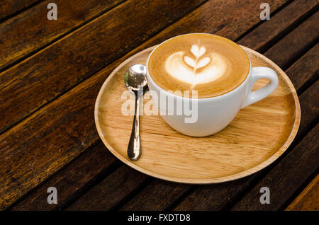Une tasse de café avec motif coeur dans une tasse blanche sur fond de bois.Close up Banque D'Images
