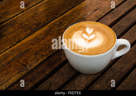 Une tasse de café avec motif coeur dans une tasse blanche sur fond de bois.Close up Banque D'Images