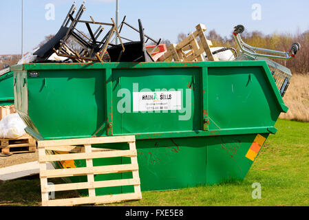 Kivik, Suède - 7 Avril, 2016 : métal vert récipient plein de junk de magasins à proximité. Logo Ragn-Sells sur le contenant. Banque D'Images