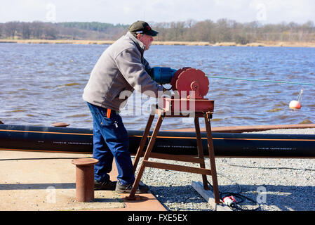 Karlskrona, Suède - 7 Avril 2016 : Assemblée Générale de conduite d'égout sous-marine en zone publique. Ici un homme est à l'aide d'un treuil motorisé Banque D'Images