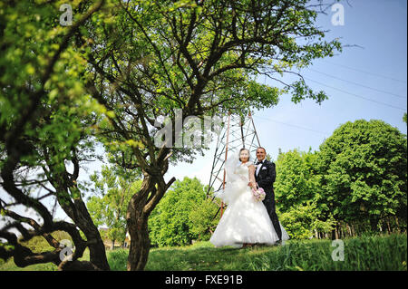 La mode happy wedding couple hugging tour électrique de fond et attend at camera Banque D'Images