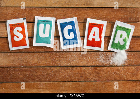 Sachets de sucre sur plancher en bois Banque D'Images