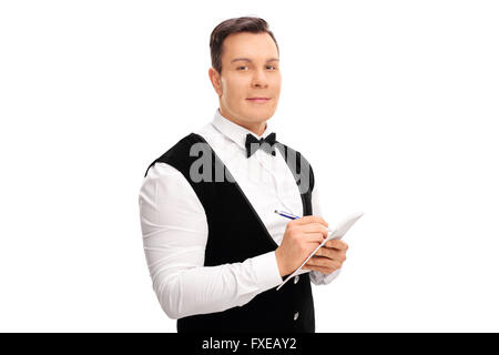 Jeune serveur écrit une commande dans un bloc-notes et regardant la caméra isolé sur fond blanc Banque D'Images