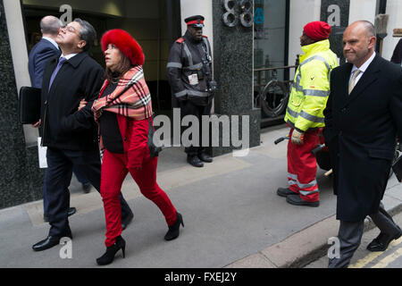 Femme portant un costume rouge et fur hat est dirigé par son partenaire à travers la ville, bras dessus bras dessous, le 23 février 2016 à Londres, au Royaume-Uni. Elle n'est pas au courant qu'elle est en interaction et la juxtaposition d'autres éléments rouge dans la rue. Banque D'Images