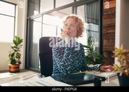 Portrait of young female designer installée à son bureau à l'écart et la pensée. Banque D'Images