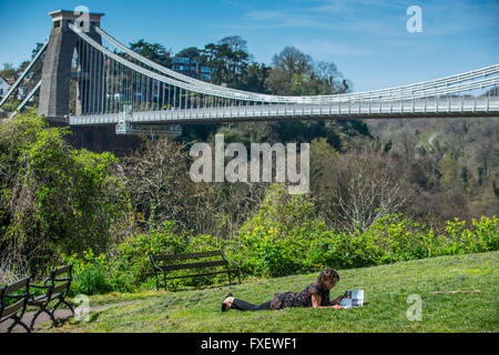 Une femme lit un magazine alors qu'elle aime le soleil et les températures chaudes à côté du pont suspendu de Clifton à Bristol. Banque D'Images