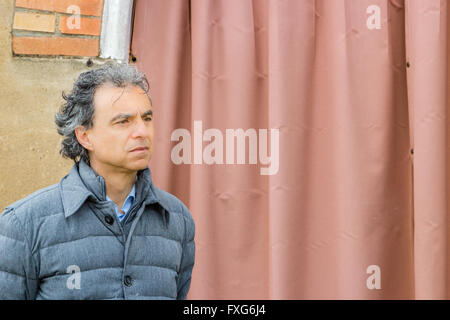 Homme Veste grise en classe pensivement devant un rideau rouge Banque D'Images