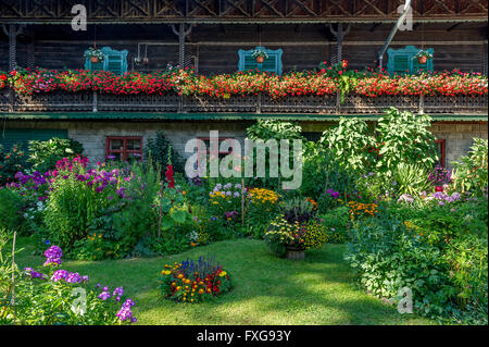 Ancienne ferme, balcon avec des géraniums (Pelargonium spec.), devant un jardin de fleurs, jardin de curé, Piesenkam, Isarwinkel Banque D'Images