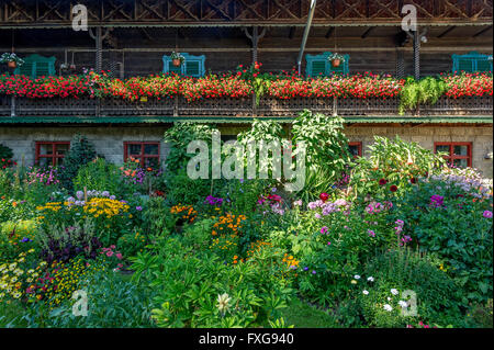 Ancienne ferme, balcon avec des géraniums (Pelargonium spec.), devant un jardin de fleurs, jardin de curé, Piesenkam, Isarwinkel Banque D'Images