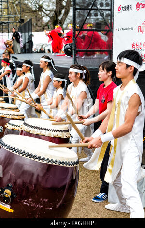 Tambours Taiko, de kumi-daiko concert. Vue de côté de la rangée d'enfants et adolescents en costume de tambours traditionnels, battant de ligne nagado-daiko tambours. Banque D'Images