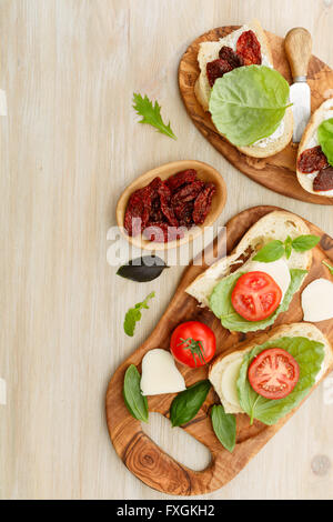 Des sandwichs ouverts de ciabatta, des tomates séchées, de la crème de fromage et de basilic feuille de laitue. Antipasti Banque D'Images