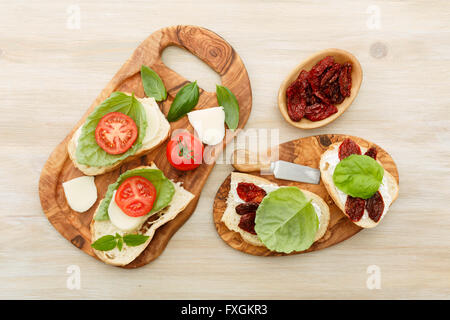 Des sandwichs ouverts de ciabatta, des tomates séchées, de la crème de fromage et de basilic feuille de laitue. Antipasti Banque D'Images