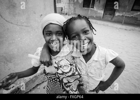 Le Mozambique, deux filles l'amitié de sourire et de poser dans une accolade, noir et blanc, B&W. Banque D'Images