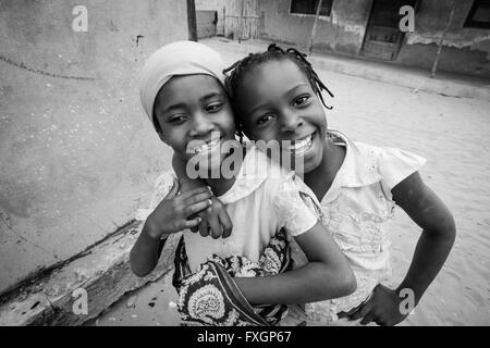 Le Mozambique, deux filles l'amitié de sourire et de poser dans une accolade, noir et blanc, B&W. Banque D'Images