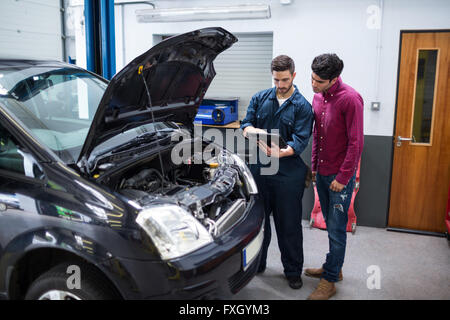 Le problème client mécanicien montrant avec voiture à l'aide d'outil de diagnostic Banque D'Images