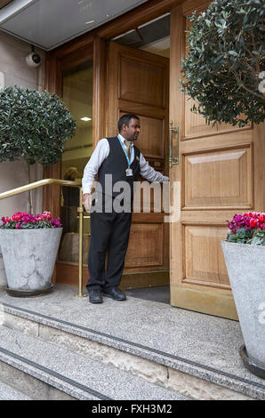 Un groom de l'hôtel ou porter l'ouverture de la porte d'un hôtel pour un client dans le Royaume-Uni. Banque D'Images