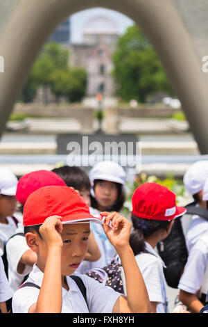 Les enfants de l'école japonaise visiter le monument cénotaphe dans le centre de Hiroshima Peace Memorial Park Banque D'Images