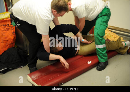 Les ambulanciers fournissent des traitements de premiers soins à un homme ivre ivre sur noir vendredi à Cardiff, Pays de Galles du Sud. Banque D'Images