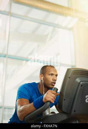 Homme déterminé sur elliptical trainer at gym Banque D'Images