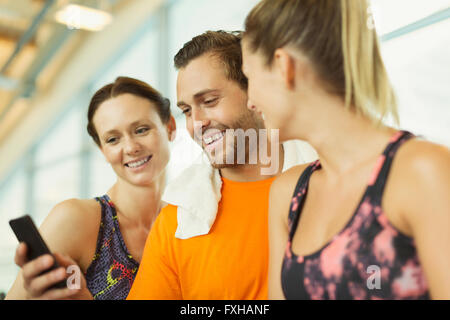 Smiling friends using cell phone at gym Banque D'Images