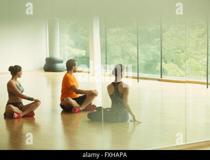 L'homme et des femmes faisant partie torsadée en studio de fitness Banque D'Images