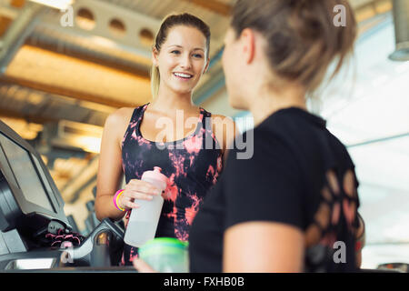 Smiling women talking and drinking water at gym Banque D'Images