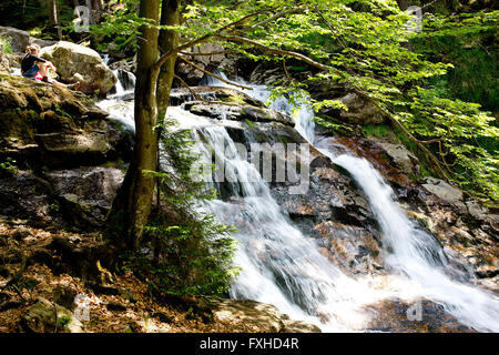 Un couple par une cascade dans le Parc National de la forêt bavaroise, Bavière, Allemagne Banque D'Images