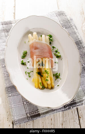 L'asperge blanche fraîchement cuit avec du beurre fondu, jambon séché à l'air et le persil haché sur une plaque Banque D'Images