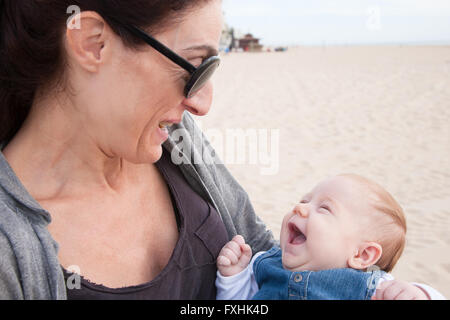 Portrait of happy brunette woman mère maillot noir gris lunettes de soleil avec deux mois d'âge bébé bleu jeans dress adopté dans son bras Banque D'Images