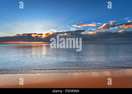 Magnifique coucher de soleil sur la mer avec reflet dans l'eau, nuages dans le ciel majestueux. Banque D'Images