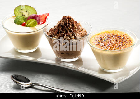 Courbes élégantes brillant en céramique de bac trois petits bols en verre rempli de crème, chocolat et fruits vanille Banque D'Images
