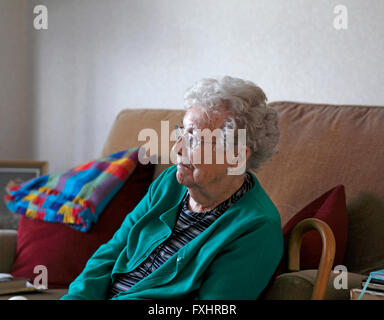 Vieille dame assise seule dans sa maison Banque D'Images
