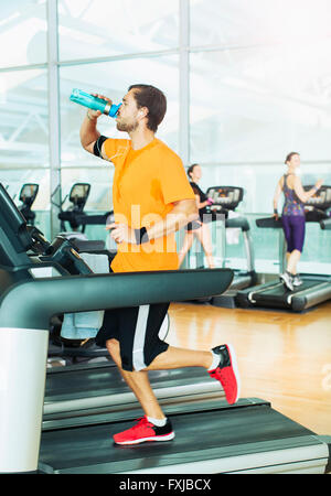 L'eau potable et à l'homme en marche sur tapis roulant à la salle de sport Banque D'Images